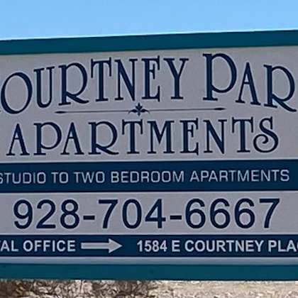 a sign for courtney park apartments with a phone number and address for the rental office.