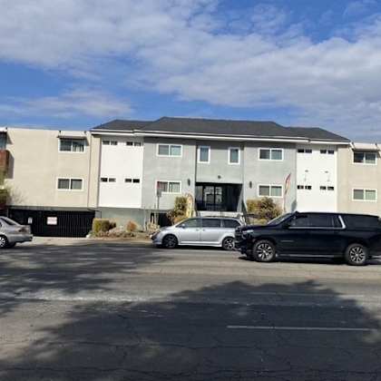 a black car is parked in front of a white building.