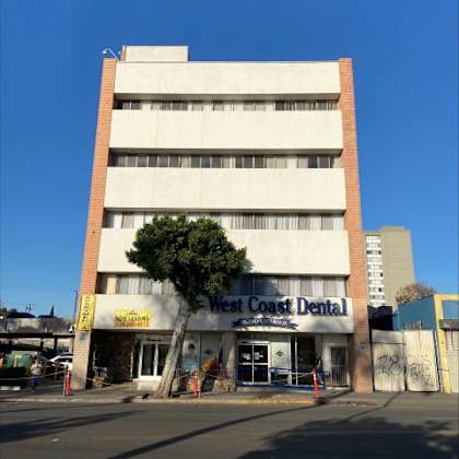 a west coast dental building with a tree in front.
