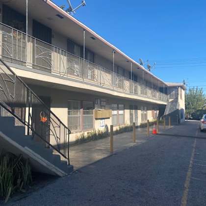 a car is parked on the street in front of a building with a balcony.