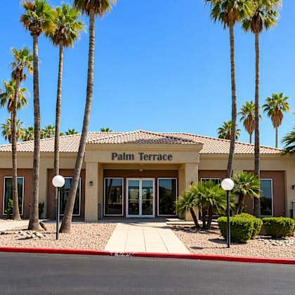 the palm terrace building is surrounded by palm trees.
