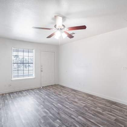 a room with a ceiling fan and a window with a view of a fence and trees.