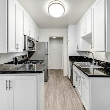 a white kitchen with white cabinets and black counter tops