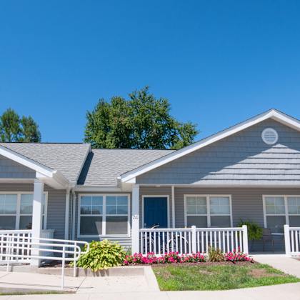 a two-story house with a white picket fence and a blue door.