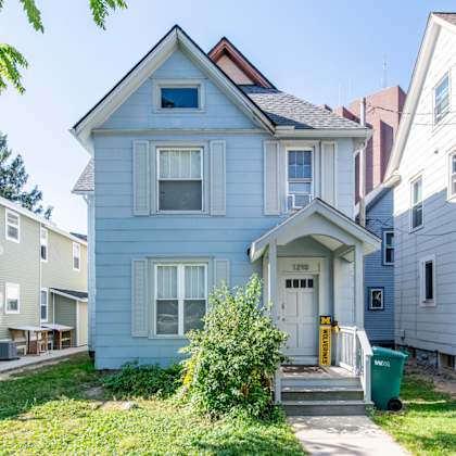 a blue house with a white door and windows is in front of other houses.