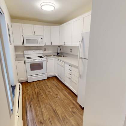 a kitchen with white cabinets and a wooden floor.