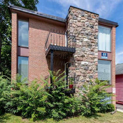 a red brick house with a balcony and a stone chimney.