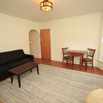 a black couch sits in a living room with a wooden coffee table in front of it.