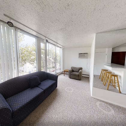 a living room with a couch, a chair, and a small kitchenette.