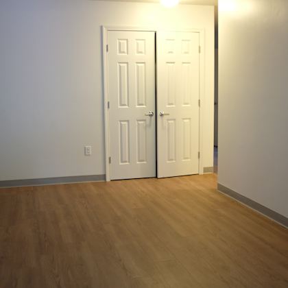 an empty living room with two doors and a wood floor