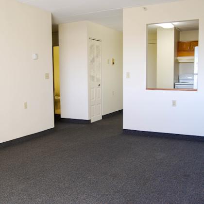 a large empty room with a door and a mirror on the wall.