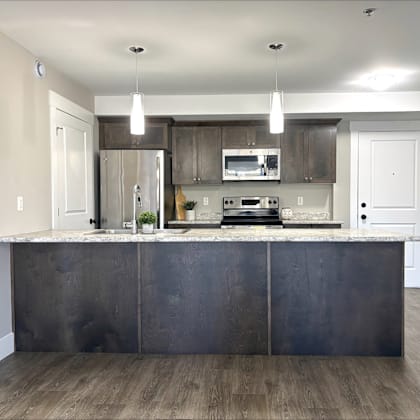 a modern kitchen with a dark island and stainless steel appliances.