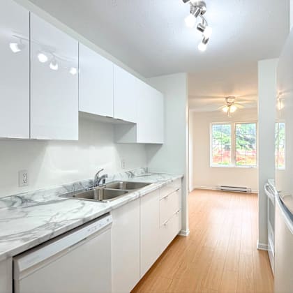 a kitchen with white cabinets and marble countertops.