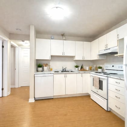 a kitchen with white appliances and wooden floors.