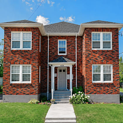 a red brick house with a grey roof and a white door.