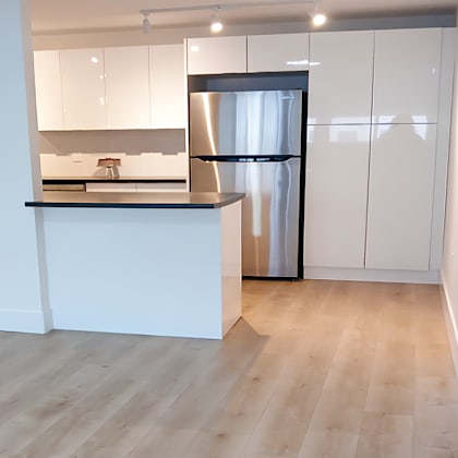 a kitchen with a white counter and a black fridge.