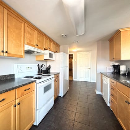a kitchen with wooden cabinets and black countertops.