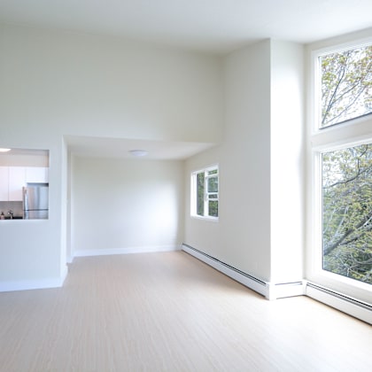 a spacious room with a large window overlooking a tree-filled area.