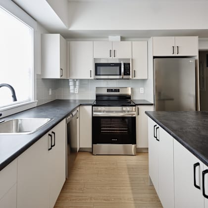 a modern kitchen with white cabinets and black countertops.