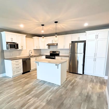 a kitchen with white cabinets and a wooden floor.