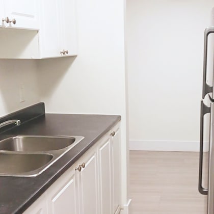 a kitchen with a black countertop and a stainless steel sink.