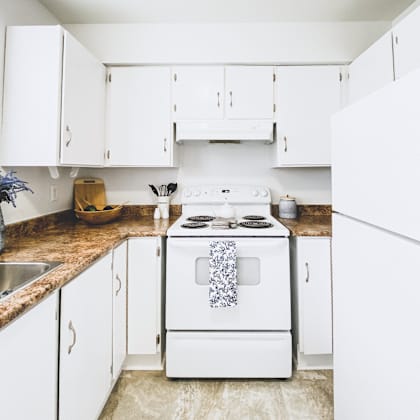 a white stove with a blue towel on it is in a kitchen with white cabinets.