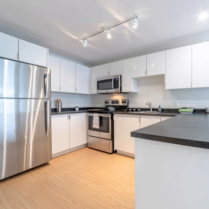 a modern kitchen with a stainless steel refrigerator and black countertops.