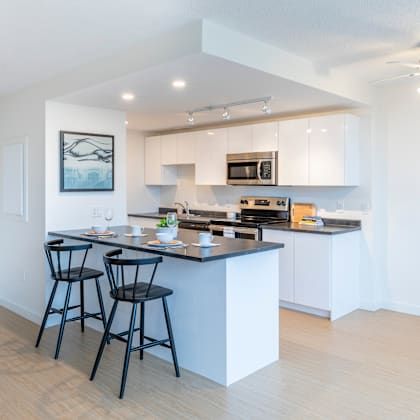 a kitchen with a bar area and two black chairs.