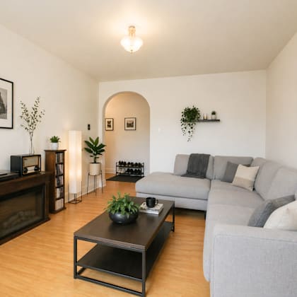 a living room with a grey couch, a coffee table, and a fireplace.