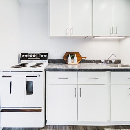 a white kitchen with a stove and cabinets.