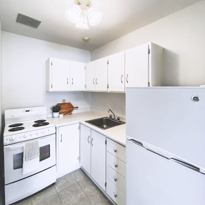 a white kitchen with a refrigerator, stove, and cabinets.