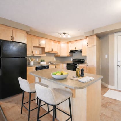 a kitchen with a black fridge, white chairs, and a marble countertop.