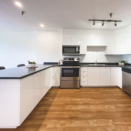 a modern kitchen with wooden floors and stainless steel appliances.