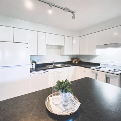 a kitchen with white cabinets and a black countertop.