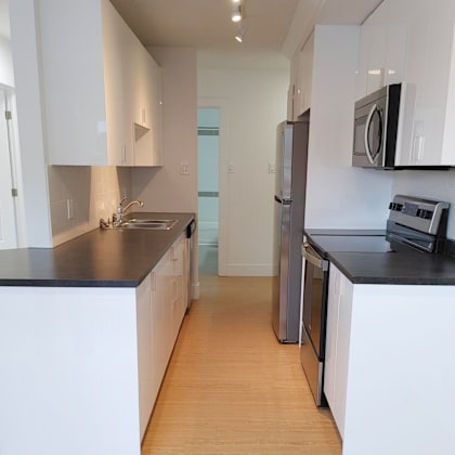 a kitchen with white cabinets and black countertops.