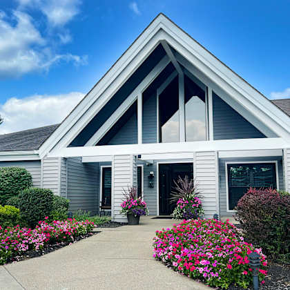 the front entrance of a white house with flowers and bushes at deercross apartments, cincinnati, oh