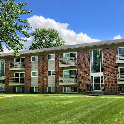 a red brick building with a green lawn in front.
