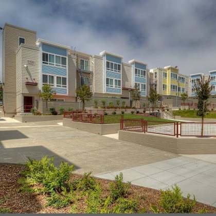 a row of modern apartment buildings with a red fence in front.