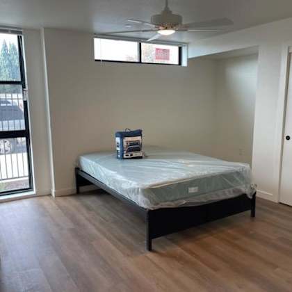 a bedroom with a bed, dresser, and sliding glass doors.