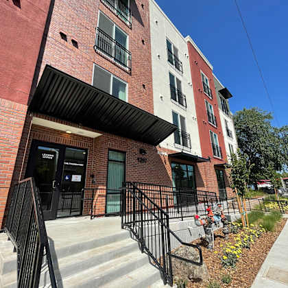a red brick building with a black awning and a black metal railing.