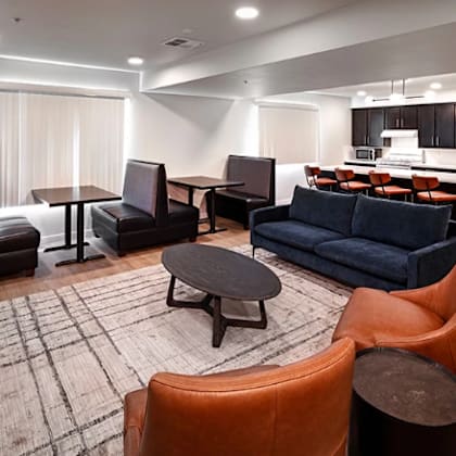 a modern living room with a blue couch and orange chairs.