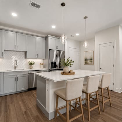 a modern kitchen with a white island and wooden chairs.