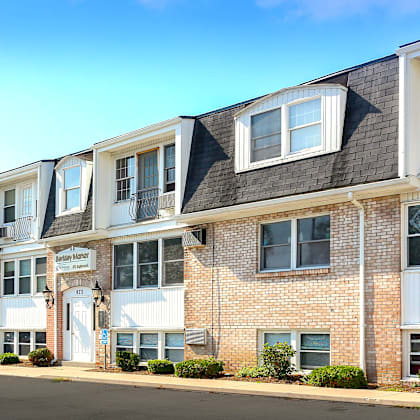 a blue car is parked in front of a row of townhouses.