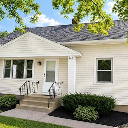 a small house with a front porch and a black railing.