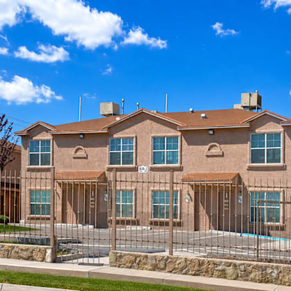 a large house with a brown roof and a pool in the front yard.