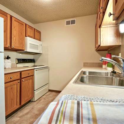 a kitchen with a white refrigerator, a microwave, a stove, and a sink.