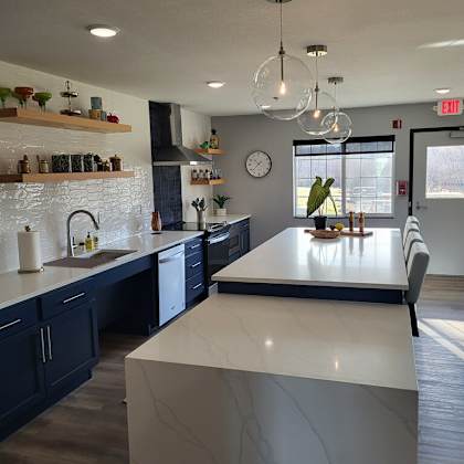 a kitchen with a white counter top and dark cabinets.