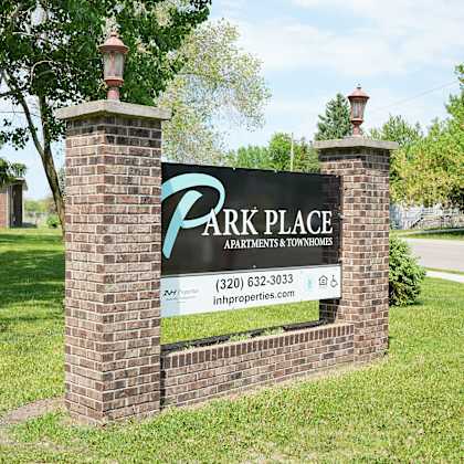 a sign for park place apartments and townhomes is displayed in front of a grassy area.