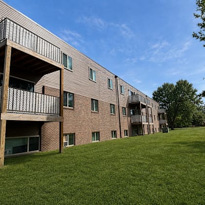 a large grassy area in front of a brick building with balconies.