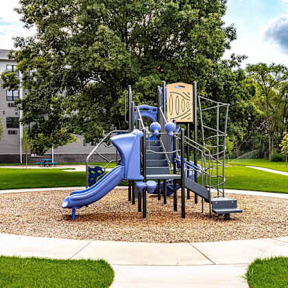 a playground with a blue slide and a yellow sign.